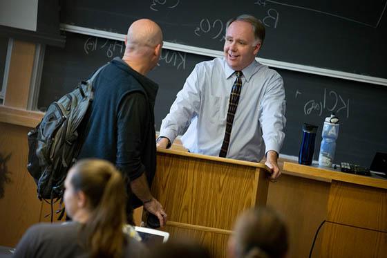 Photo of Chatham University professor leaning over a lectern, speaking with a student