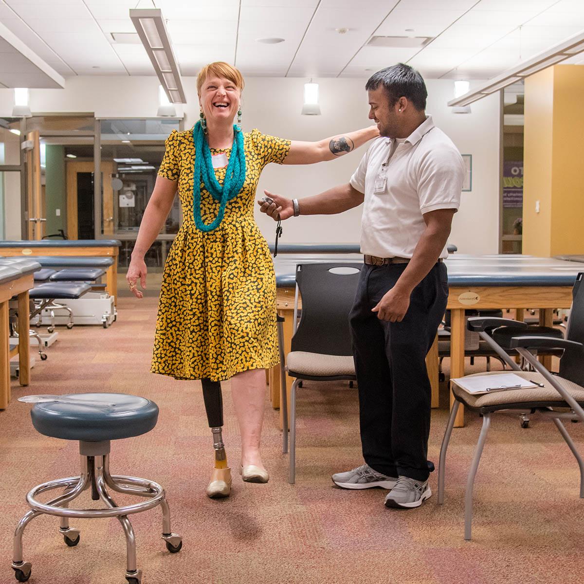 图为一名查塔姆物理治疗专业的学生在帮助一名女性截肢者试穿新的义肢