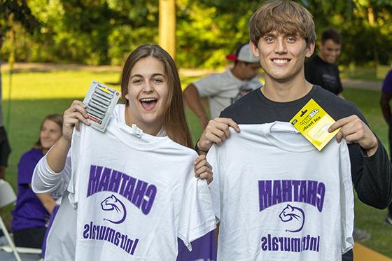 Photo of two Chatham University students holding up their intramural sports t-shirts and smiling