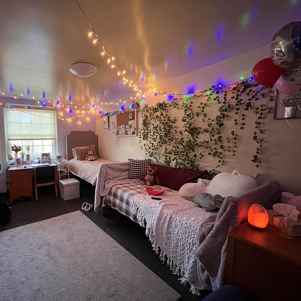 Photo of a decorated dorm room with cozy pillows and blankets and fairy lights